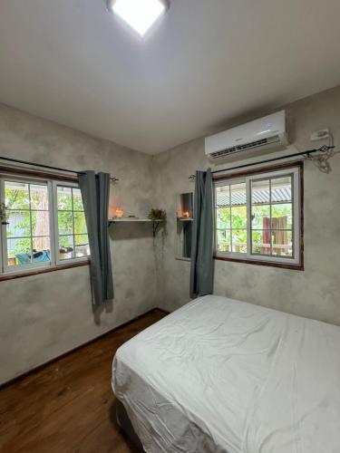 - une chambre avec un lit blanc et 2 fenêtres dans l'établissement La Villa Elena, à Carenero