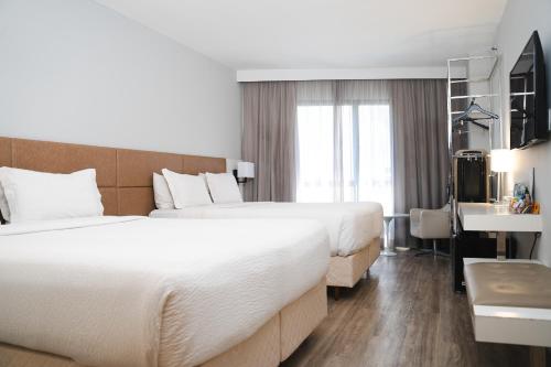 a hotel room with two beds and a desk at Radisson Rio de Janeiro Barra in Rio de Janeiro