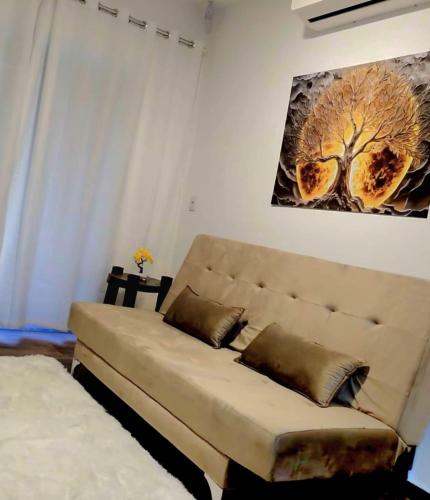 a couch in a living room with a tree painting on the wall at Recanto Wunderwald Casa Pomerode in Pomerode
