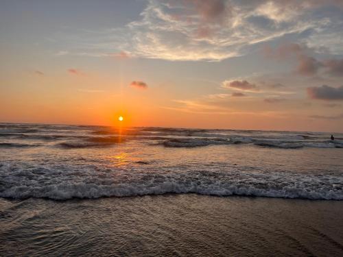 a sunset on a beach with the ocean at Morjim Sunset Guesthouse - 300 meter to Morjim Beach in Morjim