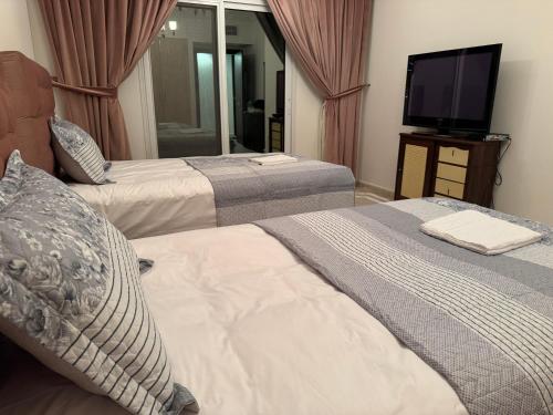 a hotel room with two beds and a television at The Family Spot in Sharjah