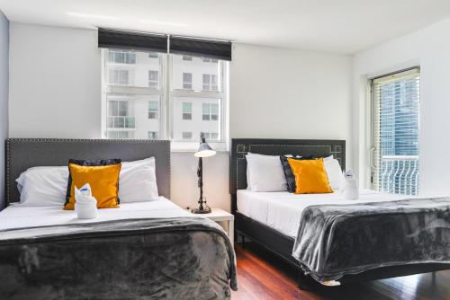 - 2 lits avec des oreillers orange et blanc dans une chambre dans l'établissement Amazing Condo Brickell with Ocean-Pool View, à Miami