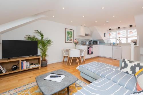 a living room with a couch and a kitchen at The Old Wire Factory - 2 bed, Close to city centre, Fast wifi, comfortable home from home in Bristol