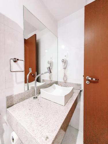 a bathroom with a sink and a mirror at Mont Blanc Suites Duque de Caxias in Duque de Caxias