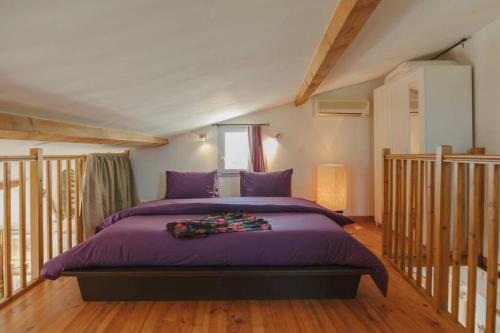 - une chambre avec un lit doté de draps violets et une fenêtre dans l'établissement Le Nid Exotique - vue sur les toits du centre-ville, à Montpellier