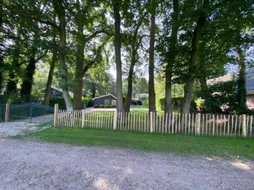 a wooden fence in front of a yard with trees at Prachtig huisje met grote tuin op de Veluwe in Wenum