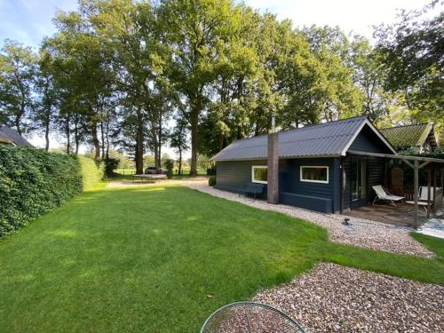 a small shed with a lawn in front of it at Prachtig huisje met grote tuin op de Veluwe in Wenum