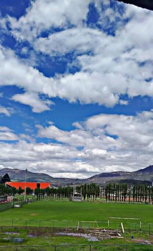 a green field with a sky with clouds at casa de campo in Ibarra