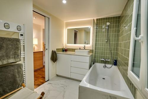 une salle de bain avec une baignoire, un lavabo et un miroir dans l'établissement Magnifique appartement, vue Grand Rex, à Paris