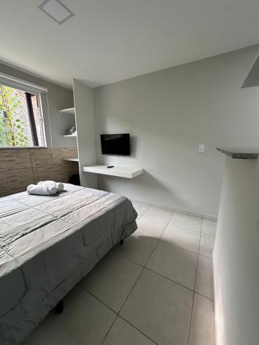 a bedroom with a bed and a desk and a television at Apto compacto e completo em Petrópolis in Petrópolis