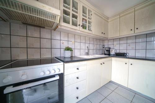 a kitchen with white cabinets and white appliances at RODI BLUE apartments in Amoudara Herakliou