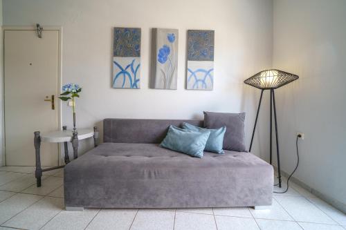 a couch in a room with three paintings on the wall at RODI BLUE apartments in Amoudara Herakliou