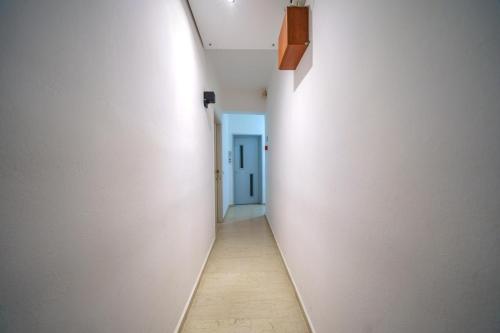 an empty corridor with a blue door in a white wall at RODI BLUE apartments in Amoudara Herakliou