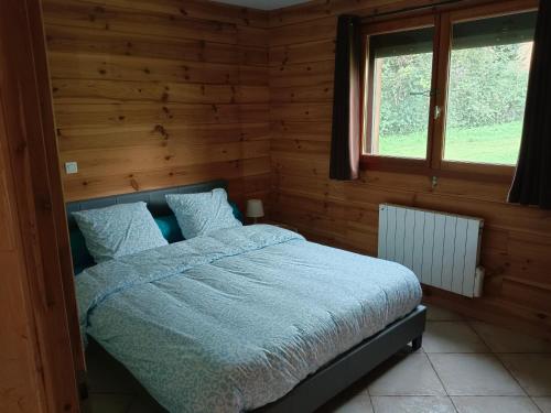 une chambre avec un lit avec des draps bleus et une fenêtre dans l'établissement Chalet 2 chambres en Savoie pour 1 à 4 personnes, à Gerbaix
