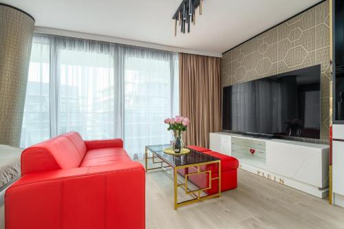 a living room with a red couch and a table at Your Holidays Waves in Międzyzdroje