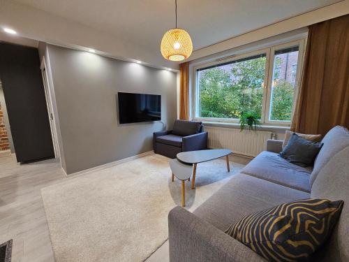 a living room with a couch and a tv at Tampere Central Cozy Stay - Two-room apartment and fully equipped FREE PARKING in Tampere