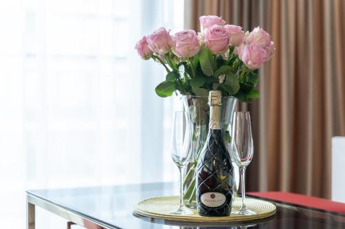 a vase of pink roses and two wine glasses at Your Holidays Waves in Międzyzdroje