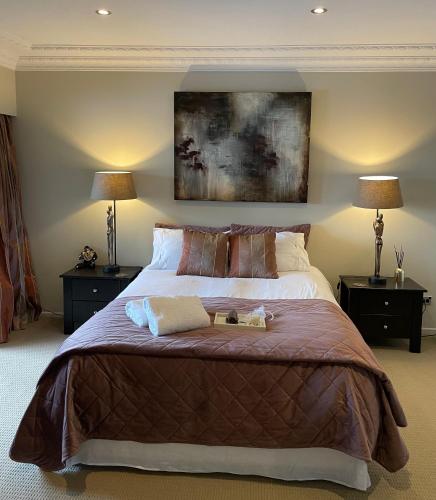 a bedroom with a large bed with two lamps at Secluded Bays Home in Auckland