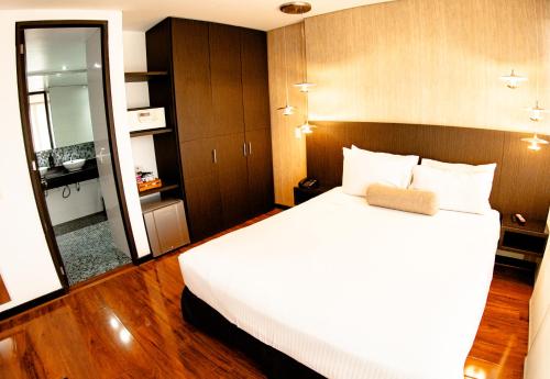 a bedroom with a large white bed and a mirror at One Sixteen Hotel in Bogotá