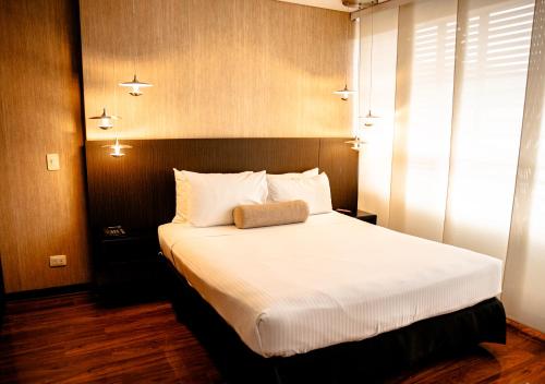 a bedroom with a large bed with white sheets at One Sixteen Hotel in Bogotá