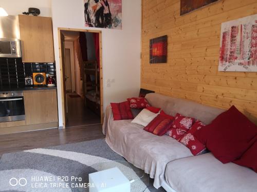 - un salon avec un canapé et des oreillers rouges dans l'établissement Charmant appartement Serre-Chevalier, à La Salle Les Alpes