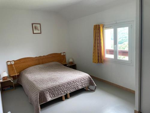 een kleine slaapkamer met een bed en een raam bij Chalet lac de la Raviege vue lac in La Salvetat