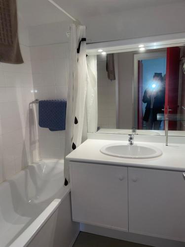 een badkamer met een wastafel, een bad en een spiegel bij Chalet lac de la Raviege vue lac in La Salvetat
