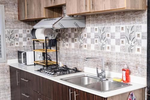 a kitchen with a sink and a stove at Meublé Hohaaa à Bastos - Anicet NEMANI in Yaoundé