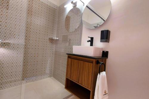a bathroom with a sink and a shower with a mirror at Comalitas Cafe y Hotel in Comala