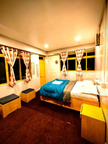 a bedroom with two beds and two windows at Hidden Monkey Stays Darjeeling, Batasia in Darjeeling