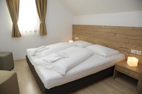 a bedroom with a white bed with a wooden headboard at Haus Stella in Mauterndorf