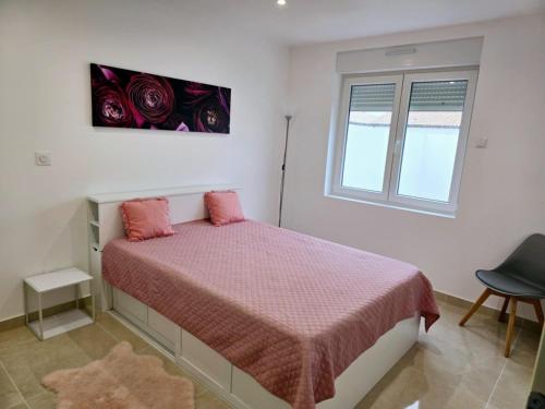 una camera da letto con un letto con lenzuola rosa e una finestra di Maison Challans a Challans