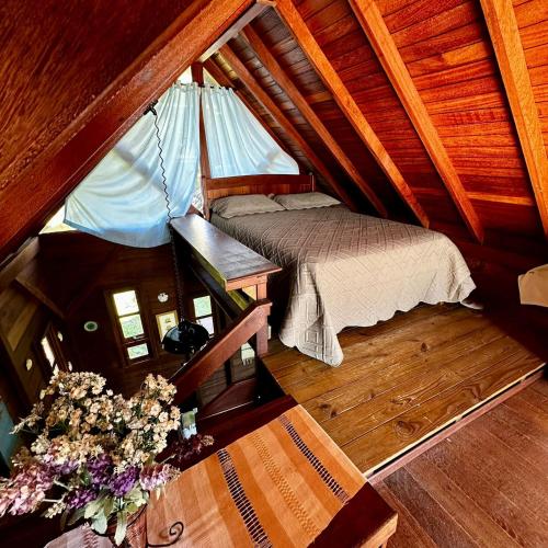 an attic room with a bed and a table and flowers at Refúgio Vista Mar Praia da Gamboa - SC in Garopaba