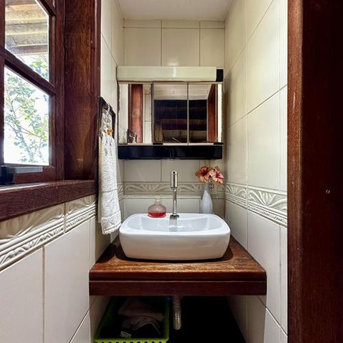 a white sink in a bathroom with a window at Refúgio Vista Mar Praia da Gamboa - SC in Garopaba