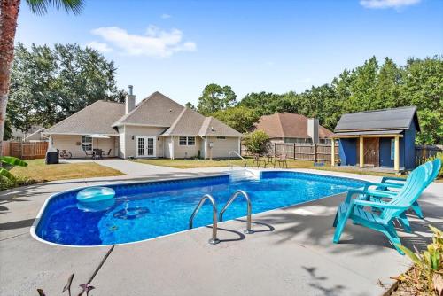 a swimming pool with a blue chair and a house at Endless Summer Retreat with Private Pool near Beach in Gautier