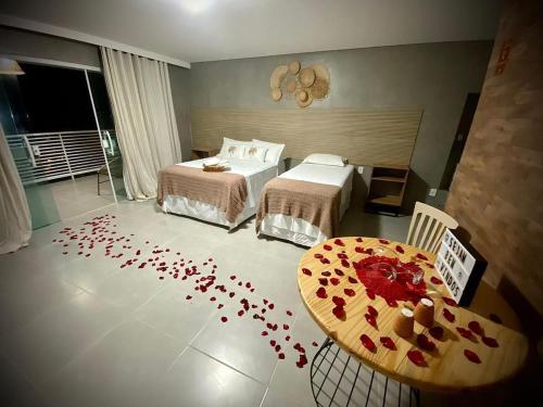 a bedroom with two beds and a table with red hearts on the floor at Pousada Villa Minduba in Japaratinga