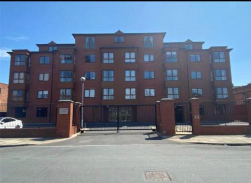 a large brick building with a fence in front of it at 6 SERVICED APARTMENTS at ST JOSEPHS COURT, CLEETHORPES by VISIT CLEETHORPES in Cleethorpes