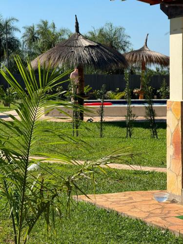 a person standing in a yard with a grass umbrella at Residencia Piri in Piribebuy