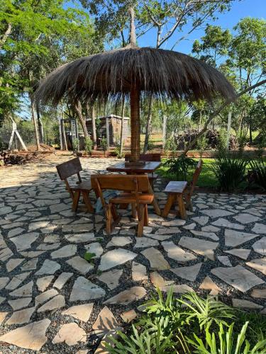 a picnic table and chairs under a straw umbrella at Residencia Piri in Piribebuy