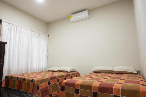 a bedroom with two beds and a window at Apartamentos Petenchel, por Aeropuerto Flores Peten no 3 in Santa Elena