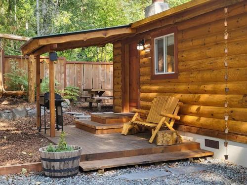 a wooden cabin with a bench on a deck at Knotty Shack- Unique Tiny Log Cabin with Hot Tub in Ashford