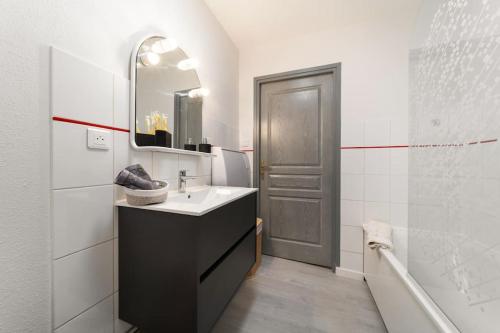 une salle de bain avec un lavabo, un miroir et une douche dans l'établissement Le Roi Lion Colmar Centre parking gratuit, à Colmar