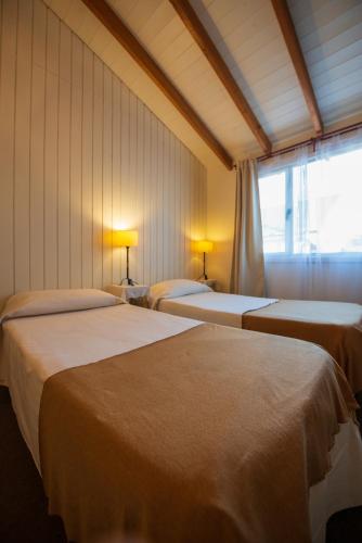 two beds in a room with a window at Los Calafates Hotel in Ushuaia