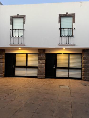 two garage doors on a building with two windows at QA Hotel in San Luis Potosí