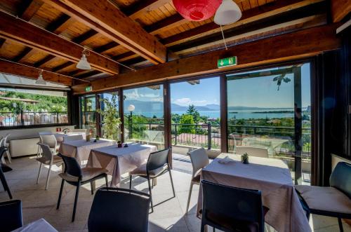 a restaurant with tables and chairs and large windows at Hotel Belvedere in Manerba del Garda