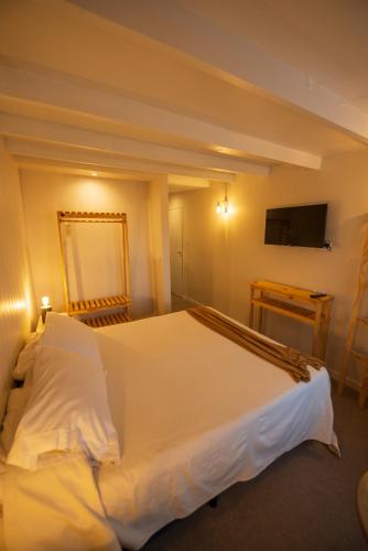 a bedroom with a white bed and a television at Los Calafates Hotel in Ushuaia