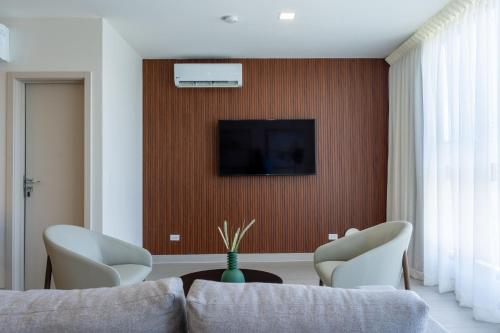 a living room with a couch and a tv on a wall at Deluxe Guest Condo Suite 1BR in Panama City