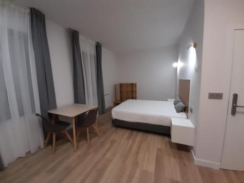 a bedroom with a bed and a desk and a table at Apartamentos Recunchos in Ourense
