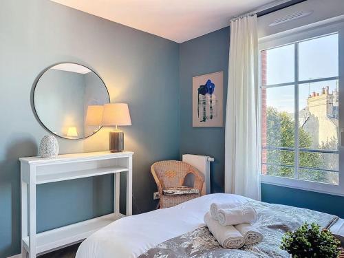 une chambre avec un lit, un miroir et une fenêtre dans l'établissement Le Royal YourHostHelper, à Deauville