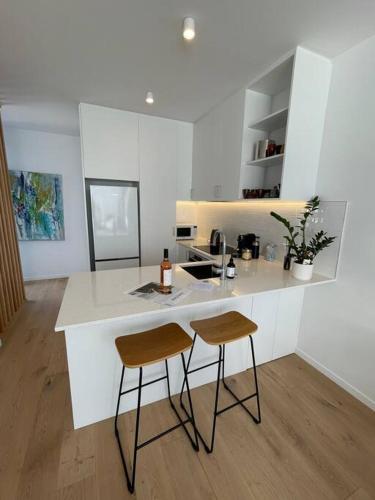a kitchen with two bar stools and a counter at Island ambience in the heart of Matakana in Matakana